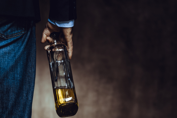 A person holding a bottle of alcohol at their side